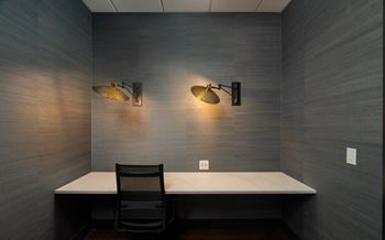 a desk in a room with two lights and a chair